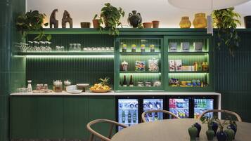 A green-themed bar area with shelves of glassware, bottles, and snacks.