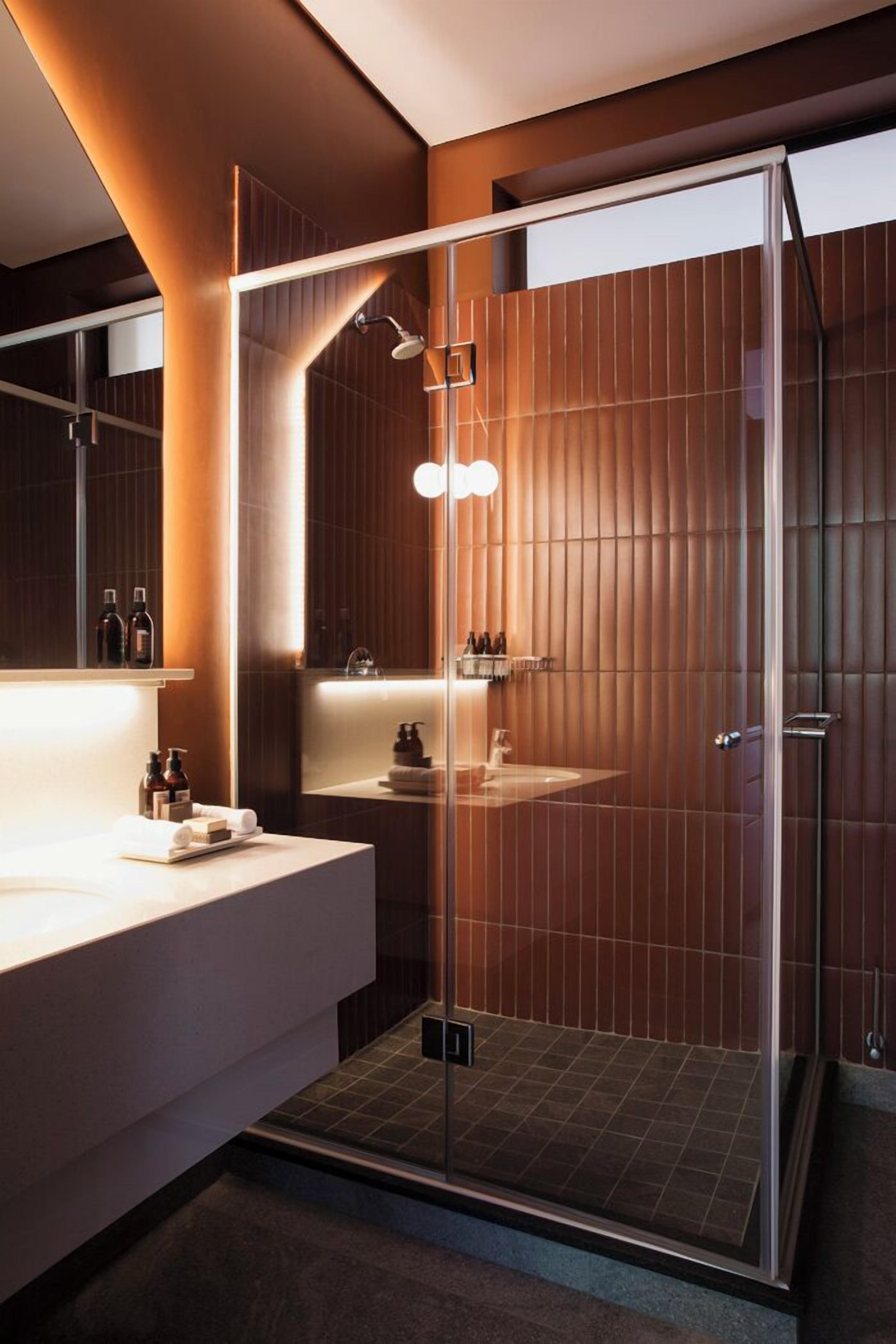 Een moderne badkamer met een glazen douchecabine, een wastafel met spiegel en een wandplank met toiletartikelen.