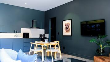 Un salon moderne comprenant un coin repas, un téléviseur à écran plat fixé au mur et une plante en pot.