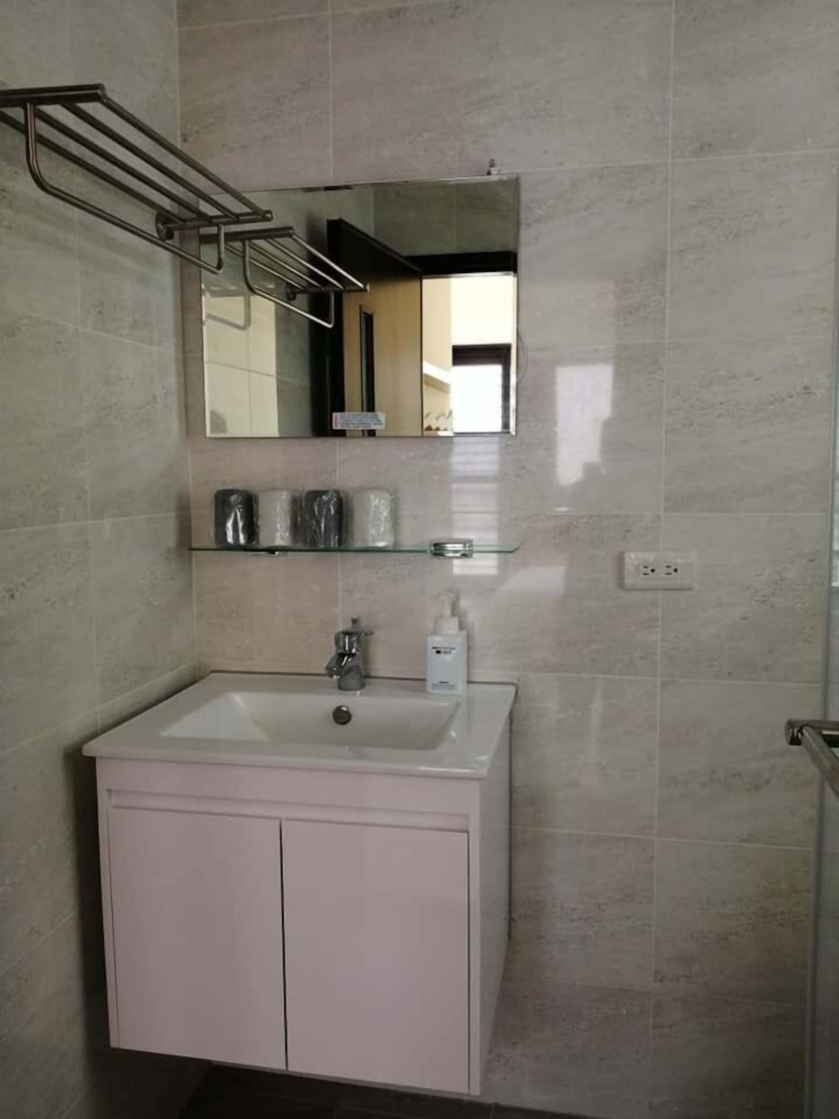 A bathroom with a white sink, a mirror above it, and a towel rack.