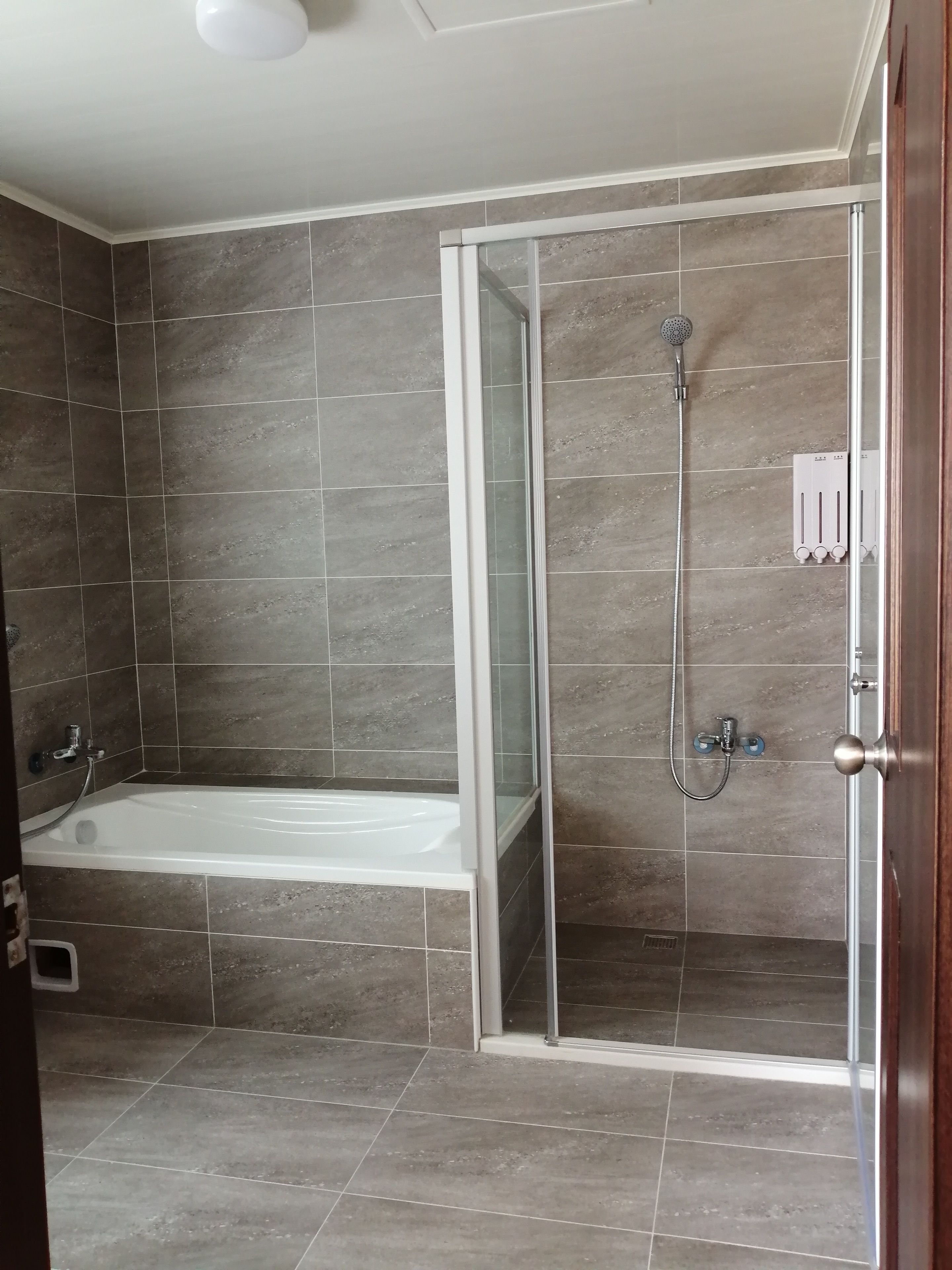 A bathroom with a bathtub, a glass-enclosed shower, and a tiled floor.
