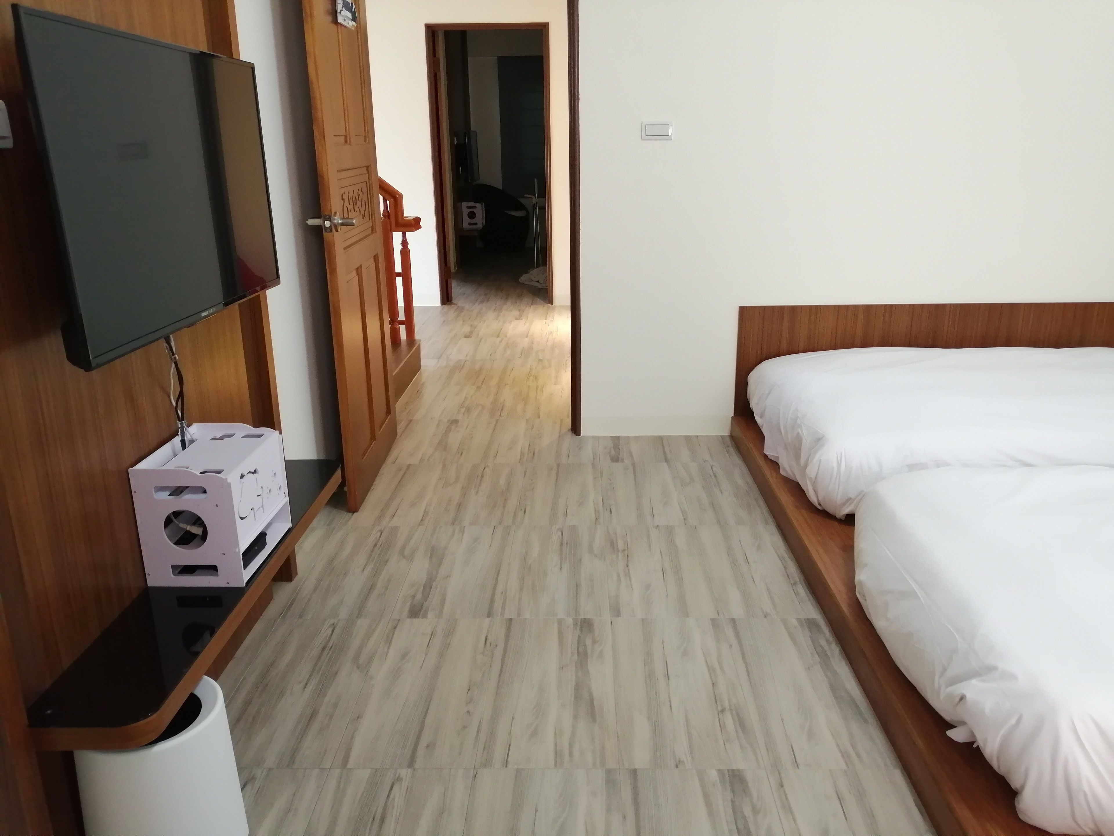 Une chambre d’hôtel avec un lit, un téléviseur fixé à un meuble en bois et une porte en bois donnant sur une autre pièce.