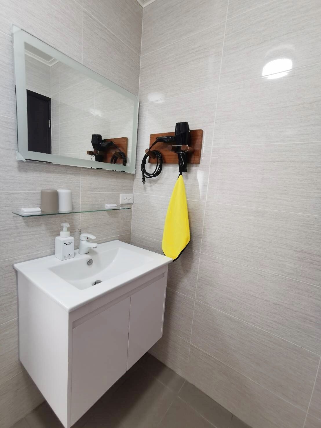 A modern bathroom with a white sink, a mirror, and a towel rack.