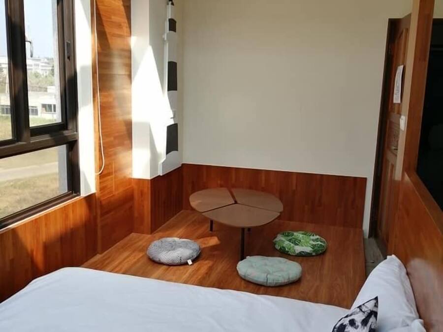 A compact room with a bed, a small round table, and two cushions.