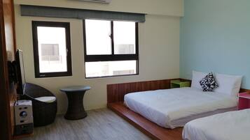 A hotel room with two beds, a small round table, a large window, and an air conditioning unit.