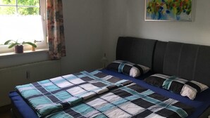 A bedroom with a bed, a window with curtains, a potted plant, and a painting on the wall. - Vacation apartment Linde (2 persons) - Ferienwohnungen May (Plankenfels)