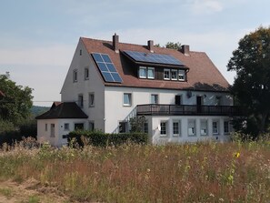 A two-story house with solar panels on the roof and a balcony. - Vacation apartment Linde (2 persons) - Ferienwohnungen May (Plankenfels)