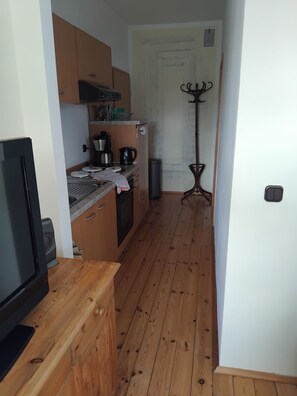 A compact kitchen with wooden cabinets, a coffee maker, and a kettle on the counter. - Vacation apartment Linde (2 persons) - Ferienwohnungen May (Plankenfels)