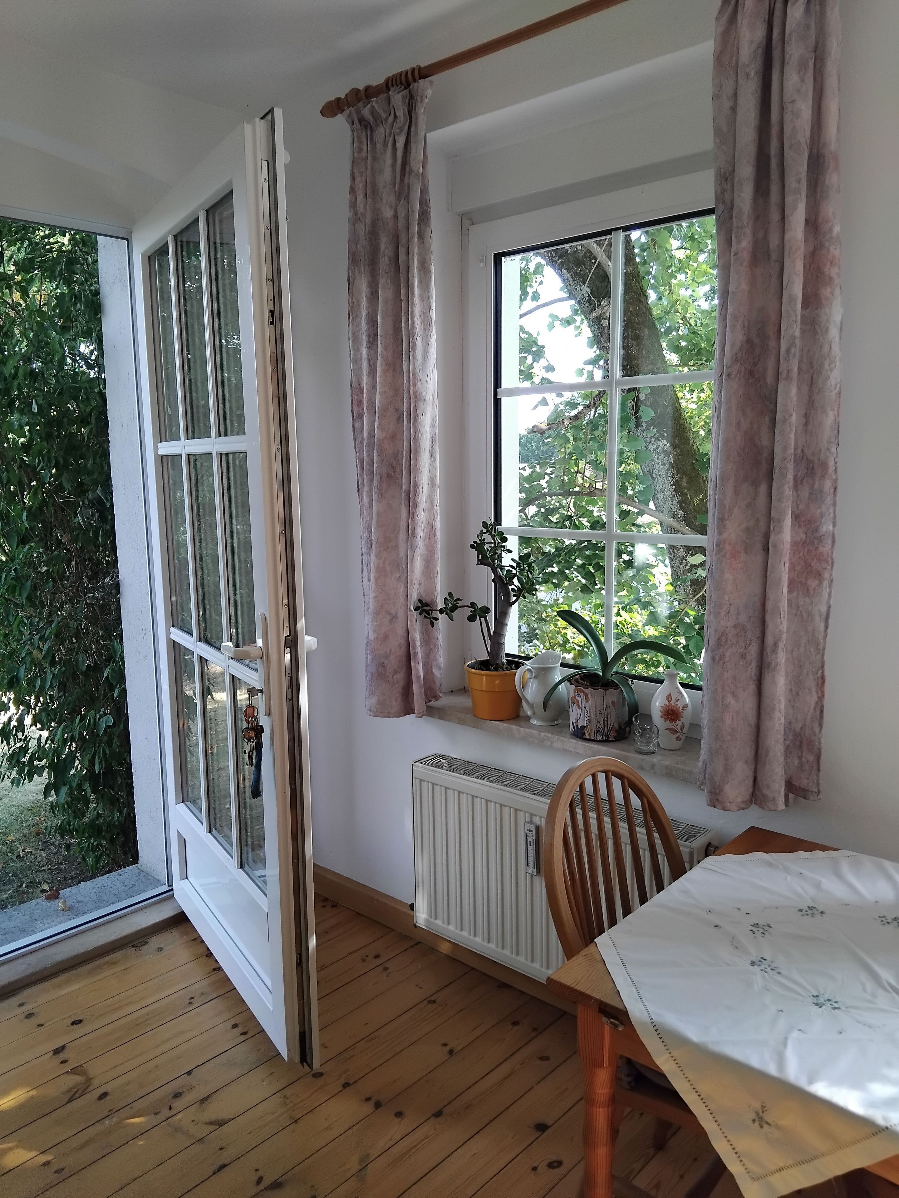 Une pièce dotée d’une grande fenêtre, d’un plancher en bois et d’une table recouverte d’une nappe blanche.
