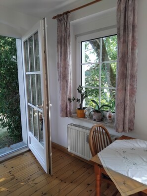 Una habitación con un ventanal grande, piso de madera y una mesa con mantel blanco.