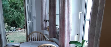A room with a wooden table and chairs, a radiator, and a window with curtains.