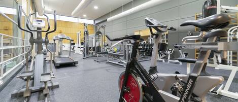 A gym with various exercise equipment, including treadmills, stationary bikes, and weight machines.