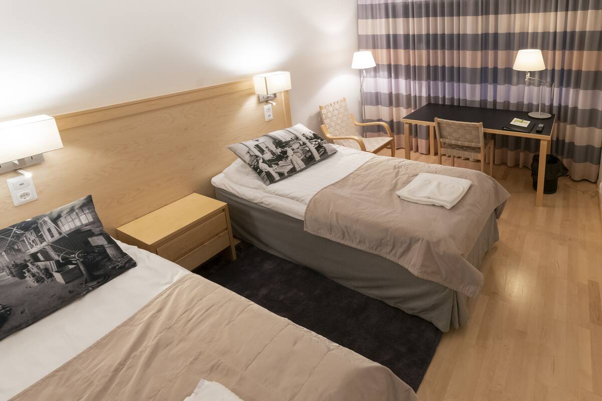 Een hotelkamer met twee bedden, een bureau, een stoel en een televisie.