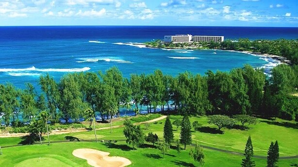 Camp de golf amb vista a l'oceà i un hotel al fons.