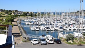 A marina with numerous boats docked, a road with parked cars, and a clear blue sky. - Nice T2 view on the port of Crouesty (Arzon)