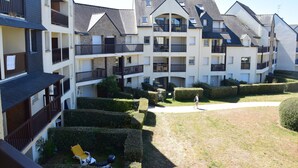 A multi-story residential building with balconies, a courtyard with hedges, and a person walking. - Nice T2 view on the port of Crouesty (Arzon)