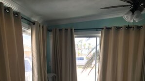 A bedroom with a bed, a chair, and a view of the outside. - Fish Heaven- 2 bed, 2 bath in KCB with boat lift, ice machine & cabana club (Key Colony Beach)