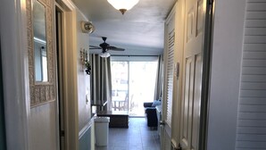 A hallway with a ceiling fan, a light fixture, and a sliding glass door leading to a patio area. - Fish Heaven- 2 bed, 2 bath in KCB with boat lift, ice machine & cabana club (Key Colony Beach)