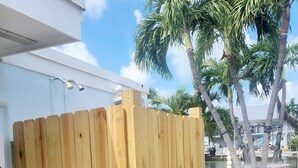 A wooden fence in front of a building with a white exterior and a clear sky. - Fish Heaven- 2 bed, 2 bath in KCB with boat lift, ice machine & cabana club (Key Colony Beach)