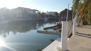 A marina with docked boats, a thatched-roof structure, and residential buildings in the background. - Fish Heaven- 2 bed, 2 bath in KCB with boat lift, ice machine & cabana club (Key Colony Beach)