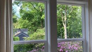 Une fenêtre donnant sur une maison et des arbres.