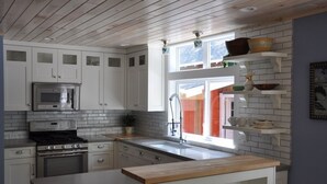 Une cuisine moderne avec des armoires blanches, un four en acier inoxydable et un plan de travail en bois.