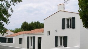 A white building with a red-tiled roof, black shutters, and a small window.