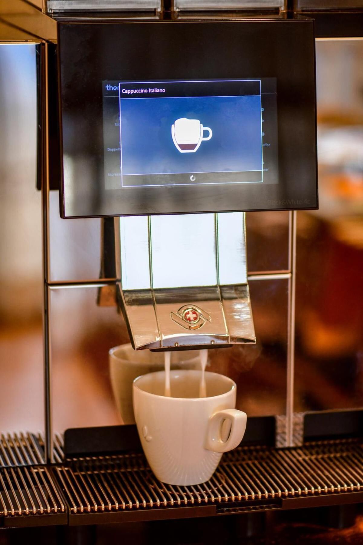 A coffee machine dispensing espresso into a white cup.