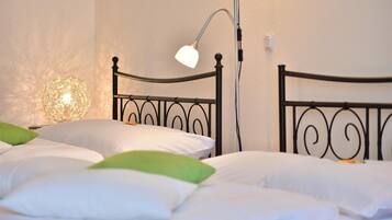 Una cama bien tendida con almohadas blancas y verdes, un cabecero de metal negro y una lámpara de noche.