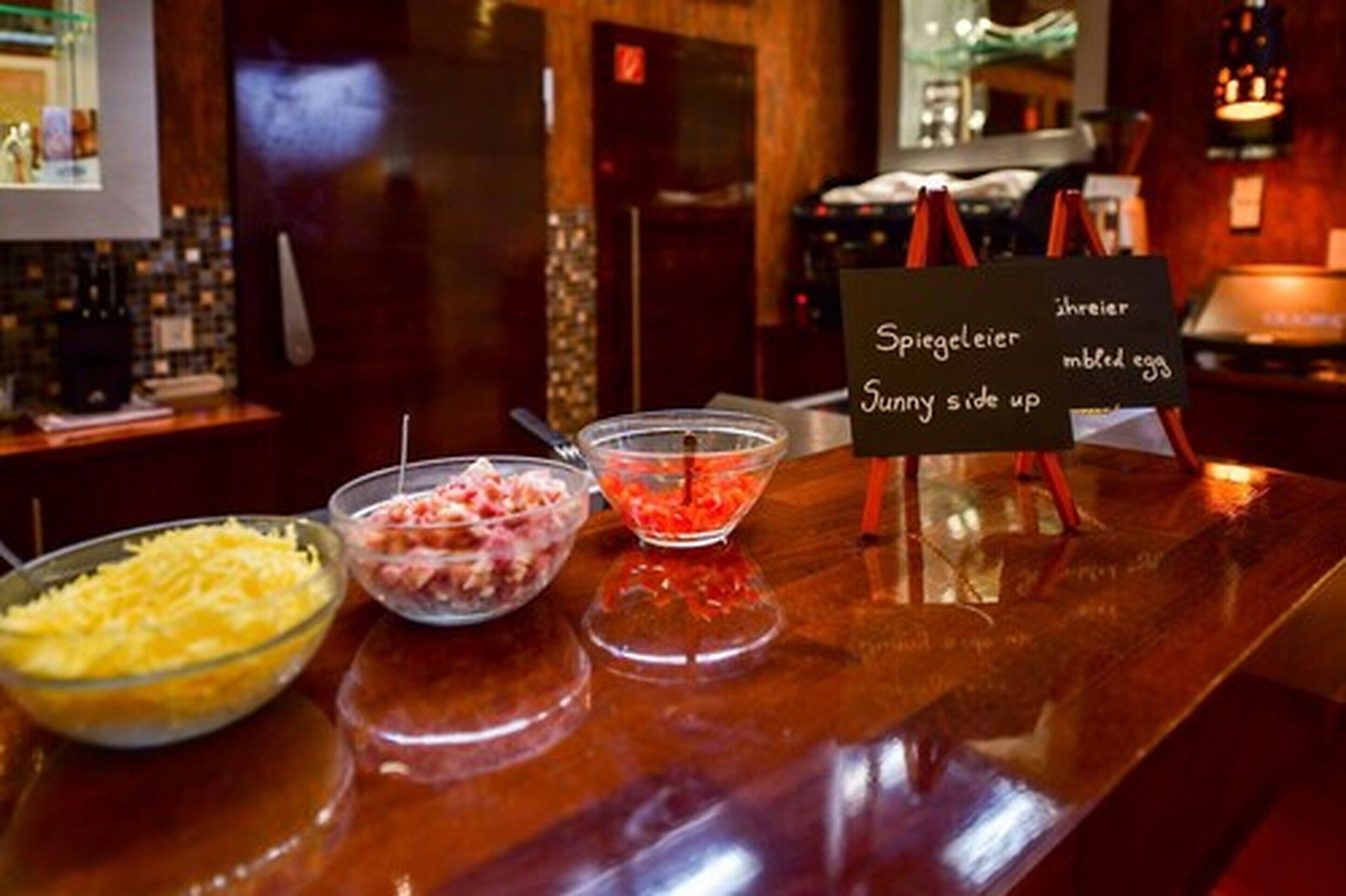Un buffet proposant trois sortes de garnitures : du fromage râpé, des dés de jambon et une sauce rouge.