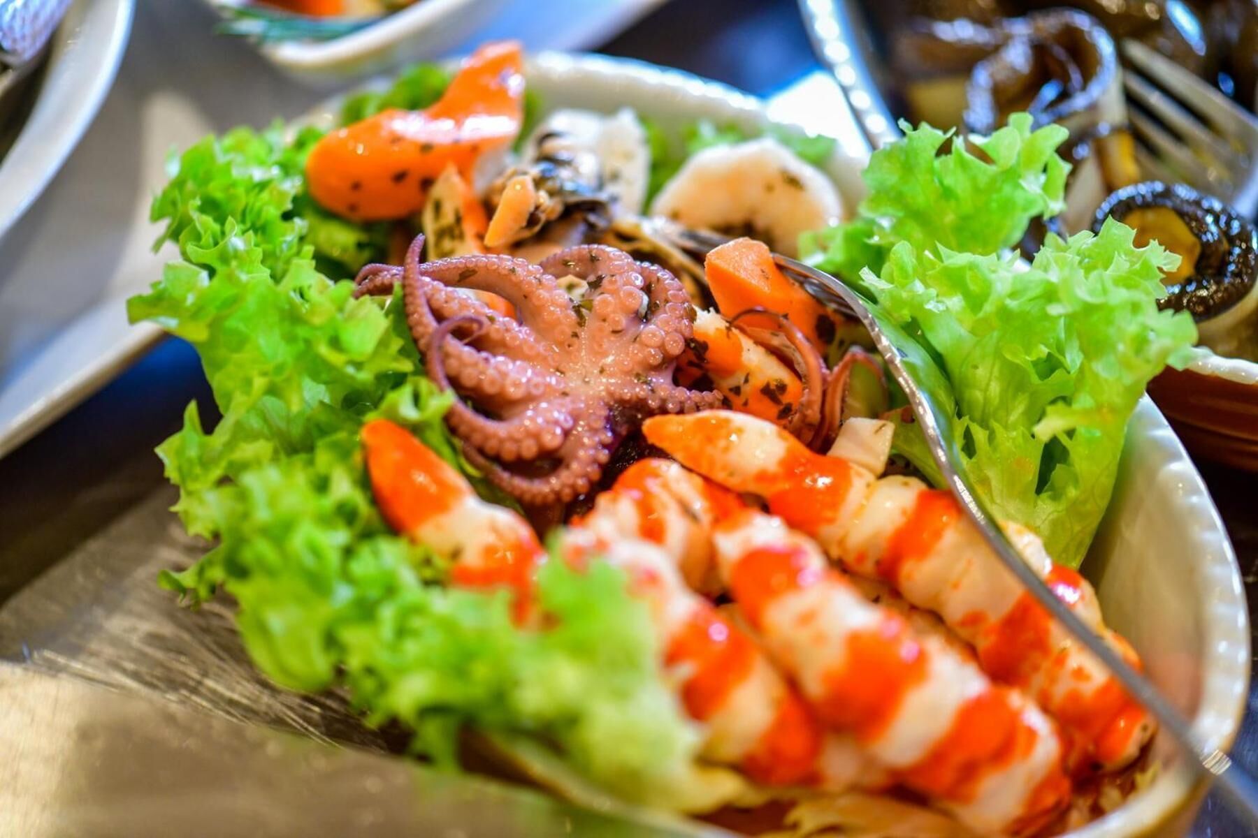 Eine Fischplatte mit Oktopusarmen, Garnelen und Muscheln auf einem Salatbett.