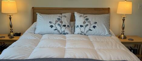 A neatly made bed with a wooden headboard, two bedside lamps, and a round mirror above.