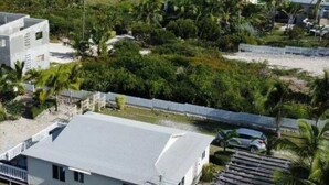 A coastal property with a white building, a fenced area, and a view of the ocean. - Modern vacation home with private yard, steps to the beach and centrally located (Mt Thompson)