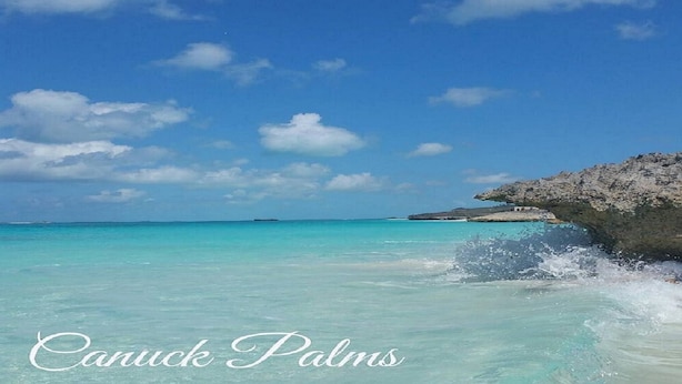 A clear view of Canuck Palms beach with turquoise waters and a rocky outcrop. - Modern vacation home with private yard, steps to the beach and centrally located (Mt Thompson)