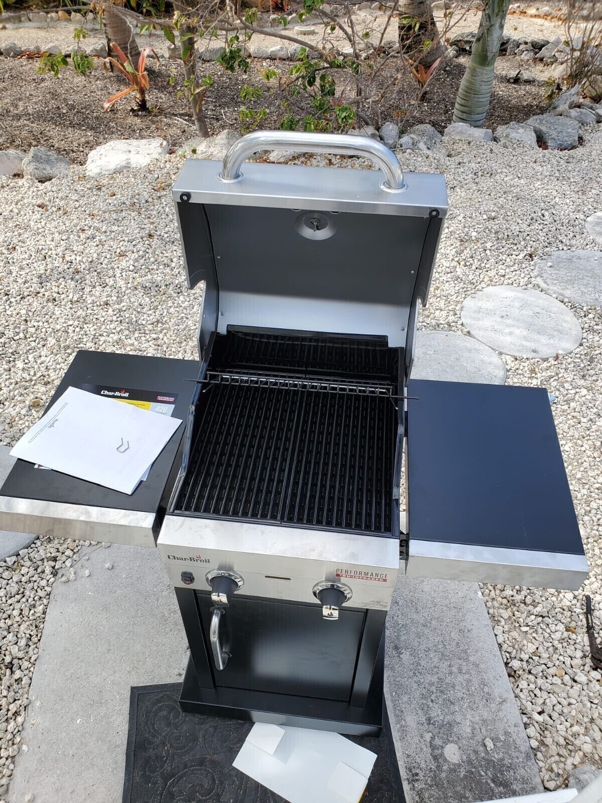 Una parrilla de gas Char-Broil con tapa negra, un quemador lateral y un panel de control con perillas.