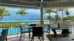 A covered outdoor area with a pool, dining table, chairs, and a view of the ocean. - Modern vacation home with private yard, steps to the beach and centrally located (Mt Thompson)