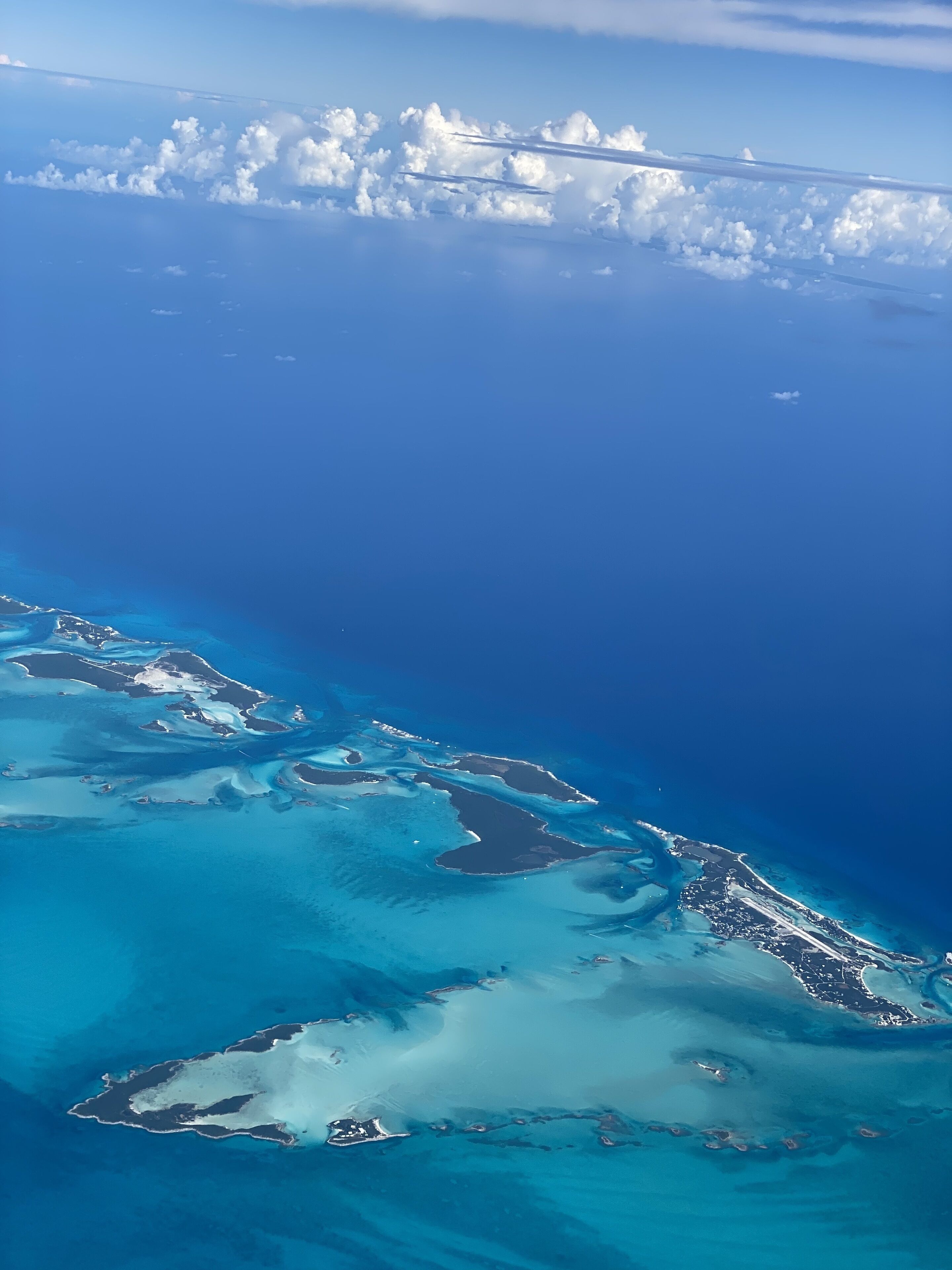 An aerial view of a coastal area with clear blue waters and several small islands.