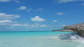 A clear view of Canuck Palms beach with turquoise waters and a rocky outcrop.
