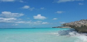 Vista despejada de la playa Canuck Palms con aguas turquesas y un promontorio rocoso.