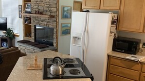 Eine Küche mit einer Wand aus Stein, einem eingebauten Herd, einem Kühlschrank und Holzschränken.