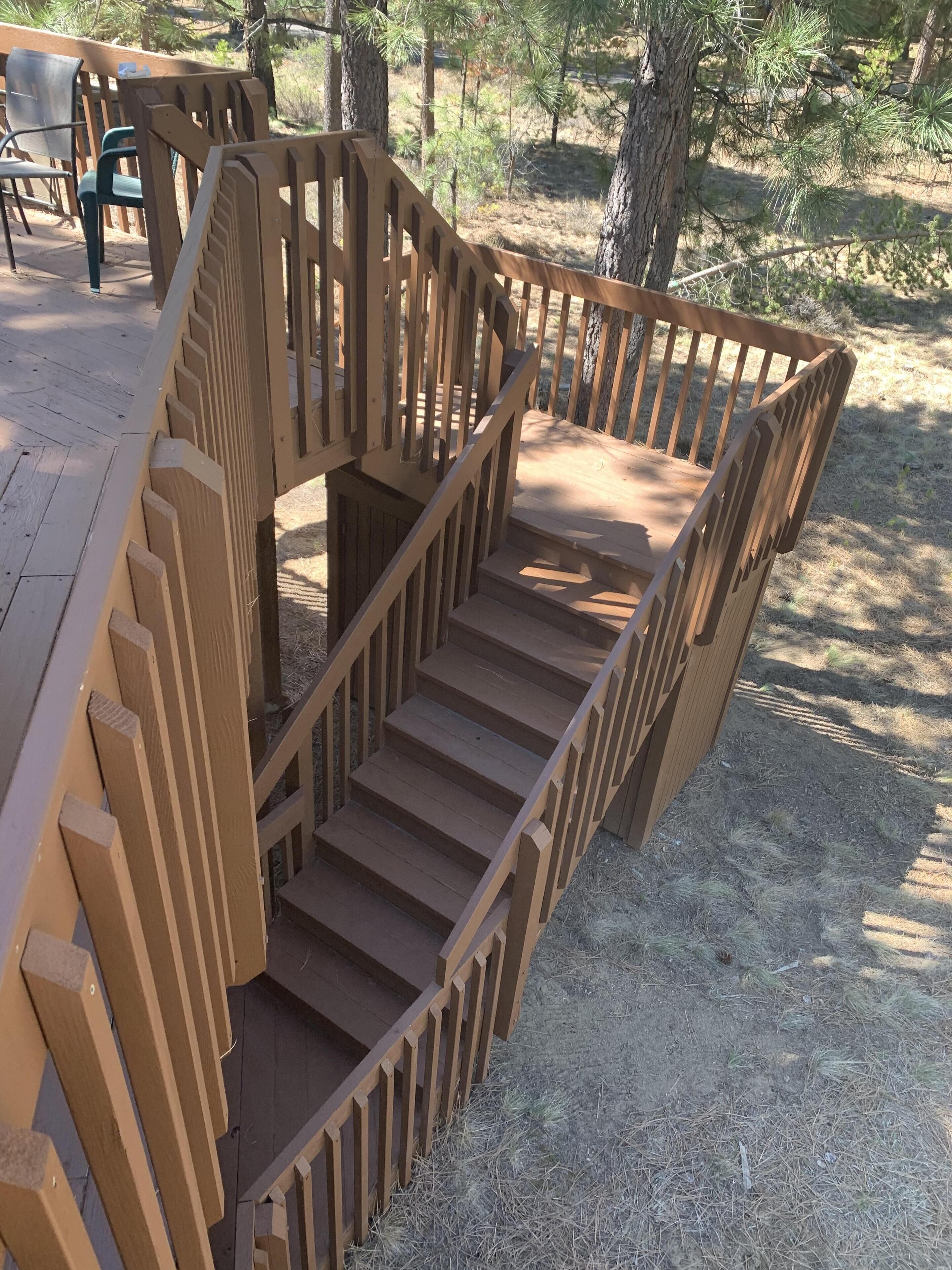 A wooden staircase with a railing leading to a deck area.
