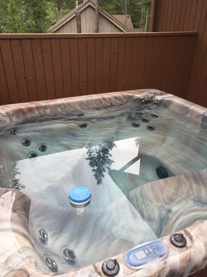 A hot tub with a control panel and multiple jets, surrounded by a wooden deck.