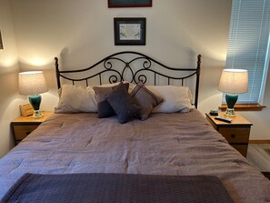 A neatly made bed with a headboard, two bedside tables with lamps, and a framed certificate on the wall.
