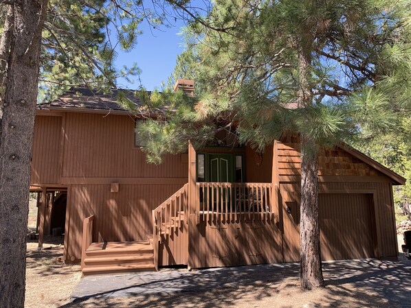 A wooden cabin with a front porch, a staircase, and a garage.