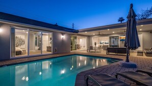 A modern outdoor pool area with a clear blue pool, lounge chairs, and a covered seating area. - PARADISE IN ARCADIA NEAR SCOTTSDALE 5BED/4BATH + HEATED POOL (Phoenix)