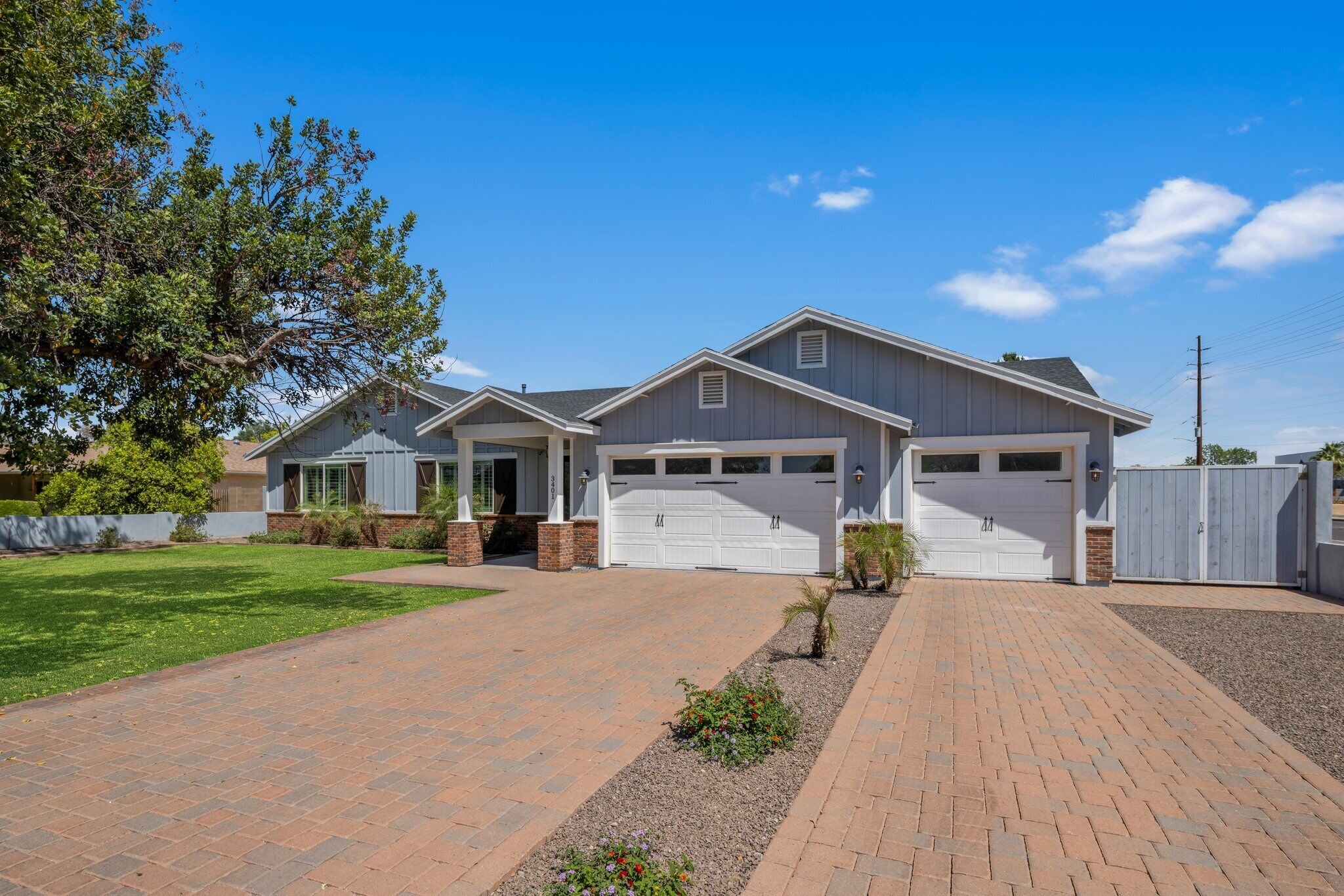 A two-story house with a garage, a brick driveway, and a well-maintained lawn.