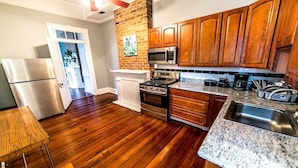 A kitchen with wooden cabinets, a stainless steel refrigerator, a microwave, an oven, and a granite countertop.