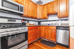 A kitchen with wooden cabinets, a stainless steel dishwasher, a built-in oven, and a microwave. - Tremé Creole Cottage near French Quarter w/ Pool (New Orleans)