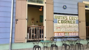 A restaurant named 'Ruth's Cozy Corner' with outdoor seating and a sign advertising home-cooked meals and sandwiches.
