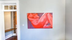 Een kamer met een schilderij aan de muur, een houten bank en een bakstenen muur.